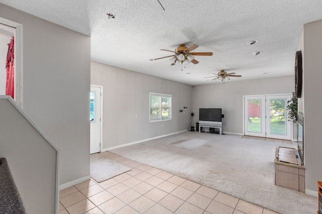 unfurnished living room with light carpet, a textured ceiling, ceiling fan, and a healthy amount of sunlight