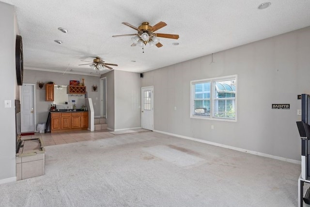 unfurnished living room with a textured ceiling, ceiling fan, and light carpet