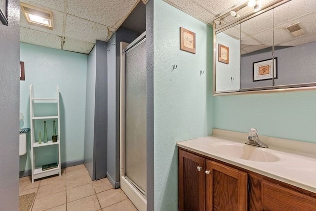 bathroom featuring tile patterned floors, vanity, a paneled ceiling, and a shower with door