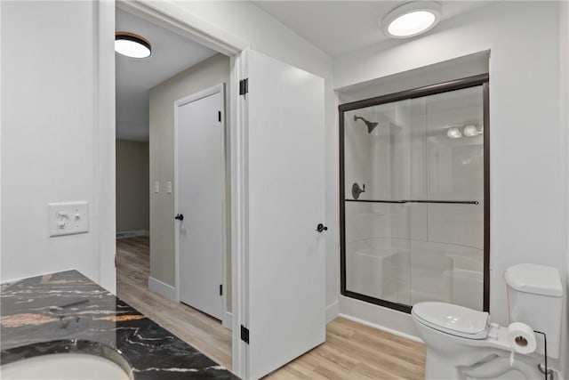 full bath featuring wood finished floors, a stall shower, and toilet