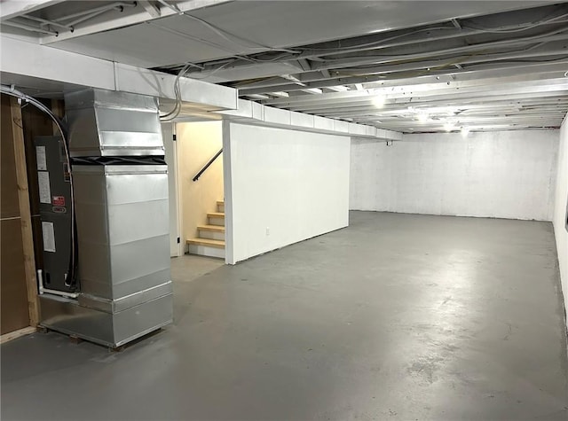 unfinished basement featuring heating unit and stairway