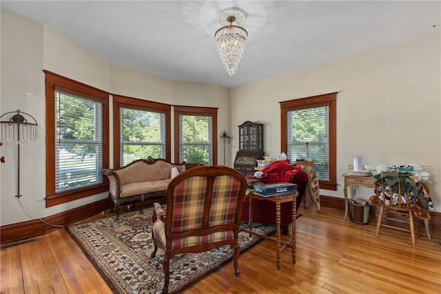 sitting room with a wealth of natural light, an inviting chandelier, and light wood-type flooring