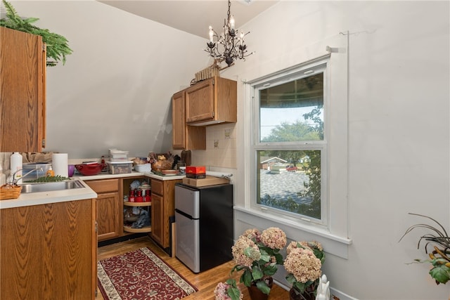 kitchen featuring pendant lighting, backsplash, stainless steel fridge, a notable chandelier, and light hardwood / wood-style floors