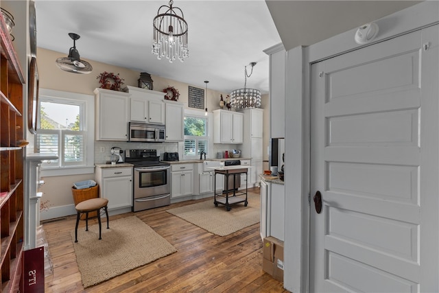 kitchen featuring white cabinets, a notable chandelier, pendant lighting, and appliances with stainless steel finishes