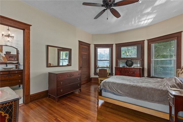 bedroom featuring a textured ceiling, dark hardwood / wood-style floors, and ceiling fan with notable chandelier