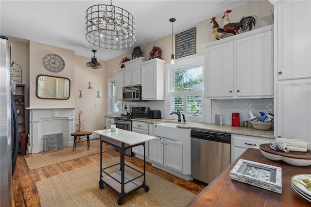 kitchen featuring white cabinets, stainless steel appliances, decorative light fixtures, and hardwood / wood-style flooring