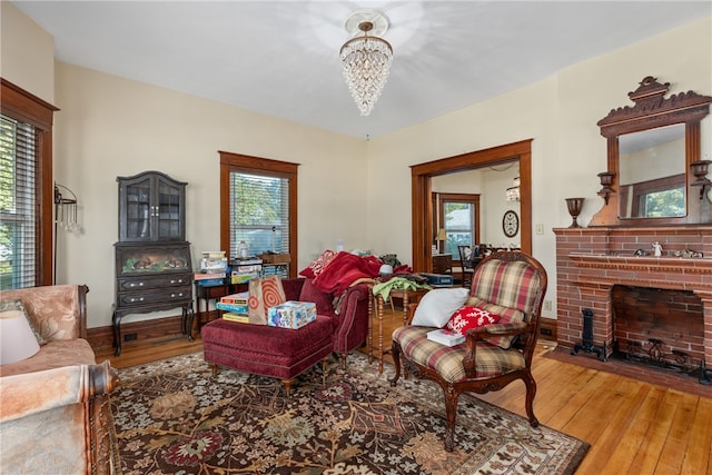 living room featuring a wealth of natural light, a fireplace, wood-type flooring, and a notable chandelier