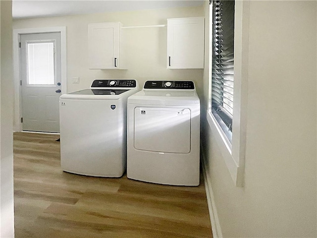 laundry room with cabinet space, light wood-style floors, and washer and dryer