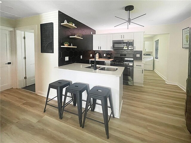 kitchen featuring appliances with stainless steel finishes, washer / clothes dryer, light wood-style flooring, and open shelves