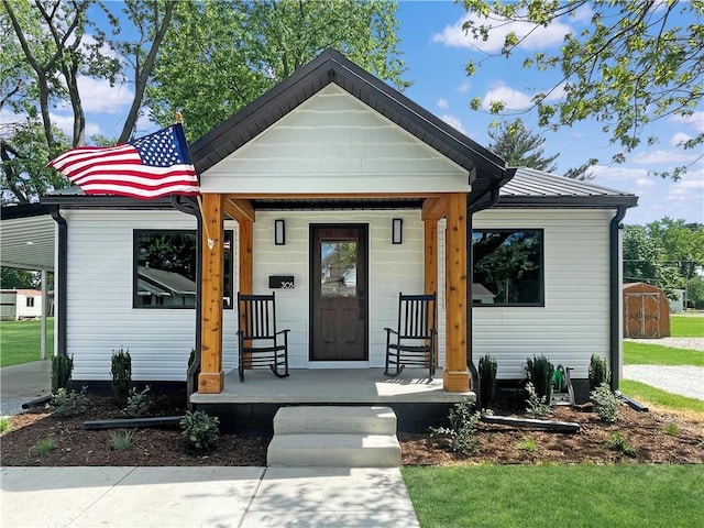 view of front of house featuring a storage shed, metal roof, covered porch, a standing seam roof, and an outdoor structure