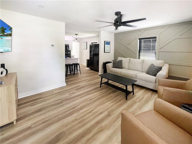 living room with ceiling fan, light wood-style flooring, and baseboards