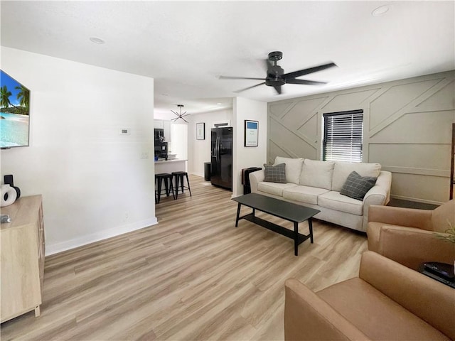 living room with baseboards, a ceiling fan, and light wood-style floors