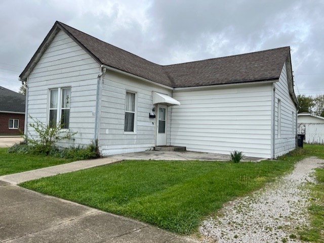 view of front of home with a front yard and roof with shingles