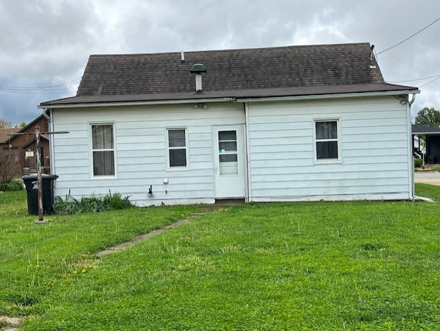 rear view of property featuring a yard and roof with shingles