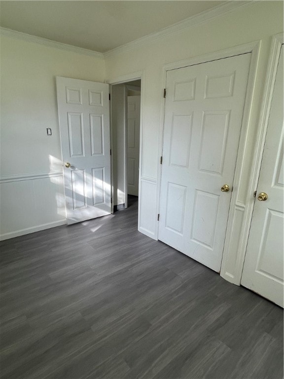 unfurnished bedroom with dark hardwood / wood-style flooring, a closet, and crown molding