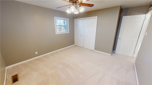 unfurnished bedroom with ceiling fan, a closet, and light carpet