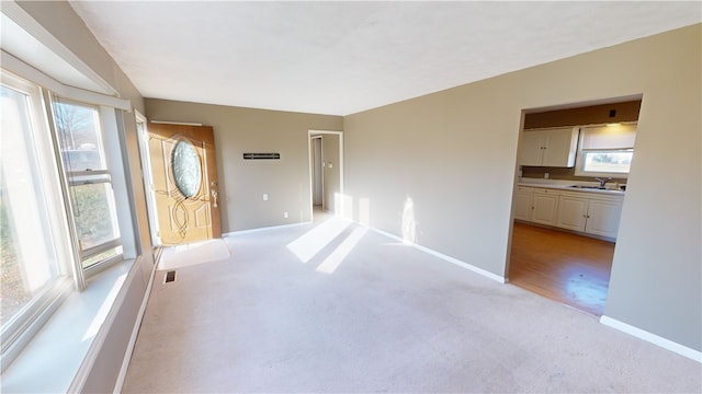 empty room featuring light carpet, plenty of natural light, and sink