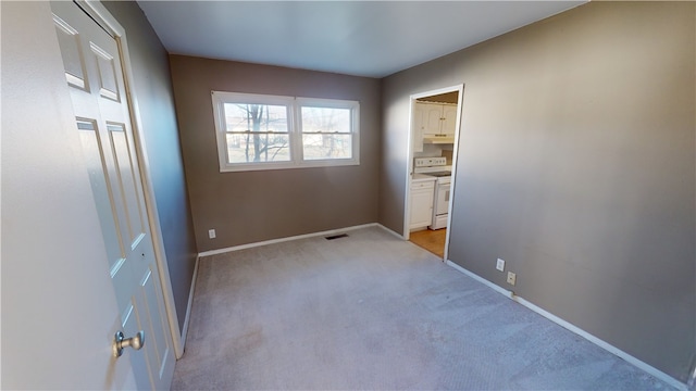 unfurnished bedroom featuring ensuite bathroom and light colored carpet