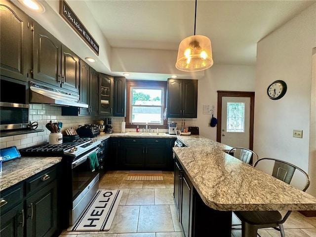 2821 Western Ave, Mattoon, IL 61938 - kitchen featuring appliances with stainless steel finishes, under cabinet range hood, backsplash, and a kitchen breakfast bar