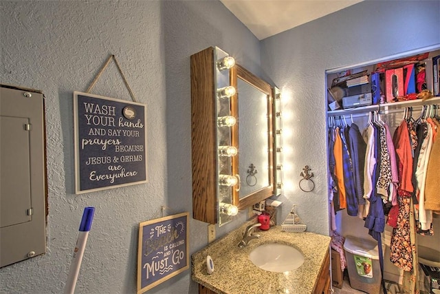 bathroom featuring electric panel, vanity, and a textured wall