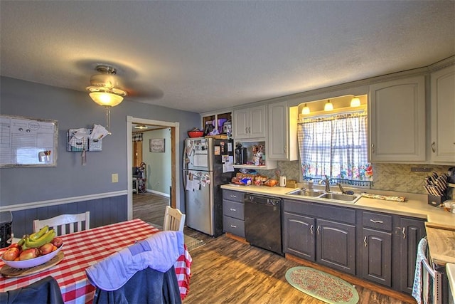 kitchen with a sink, backsplash, light countertops, appliances with stainless steel finishes, and dark wood-style flooring