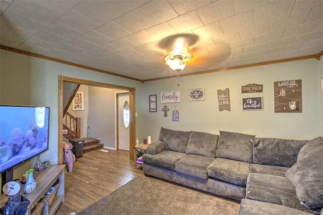 living area with stairs, wood finished floors, and ornamental molding