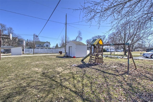 view of yard featuring fence, an outdoor structure, a shed, and a playground