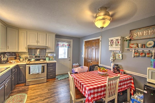 kitchen with under cabinet range hood, a textured ceiling, stainless steel range with electric cooktop, light countertops, and dark wood-style flooring