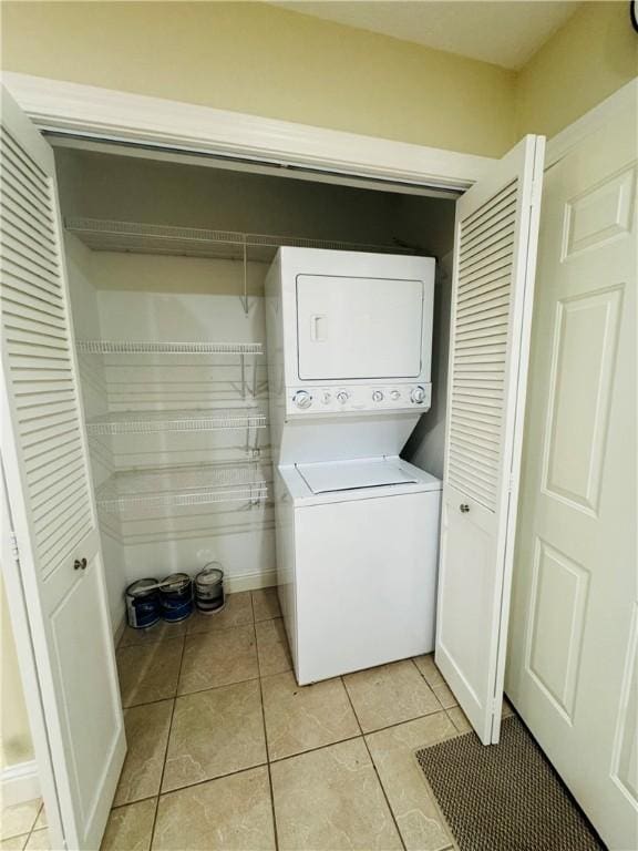 clothes washing area with stacked washer / dryer and light tile patterned floors