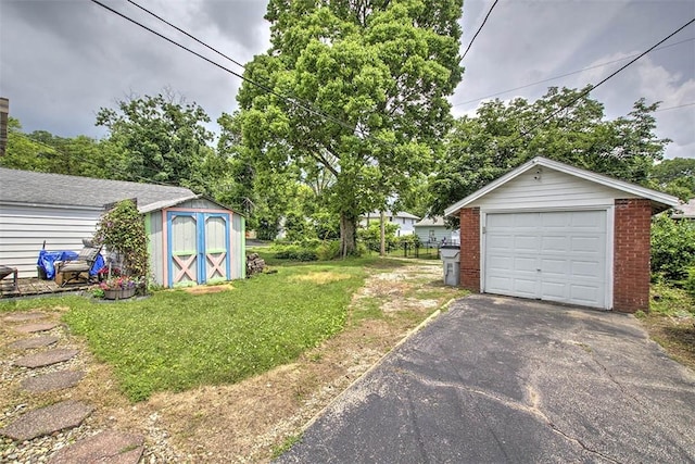 236 N Dennis Ave, Decatur, IL 62522 - view of grassy yard with a garage, asphalt driveway, and a storage shed