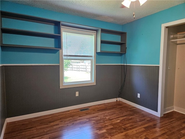 241 S Main St, Argenta, IL 62501 - unfurnished bedroom with wood finished floors, a textured ceiling, and wainscoting