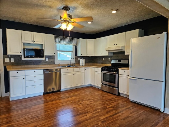 241 S Main St, Argenta, IL 62501 - kitchen featuring appliances with stainless steel finishes, under cabinet range hood, white cabinets, a ceiling fan, and dark wood-type flooring