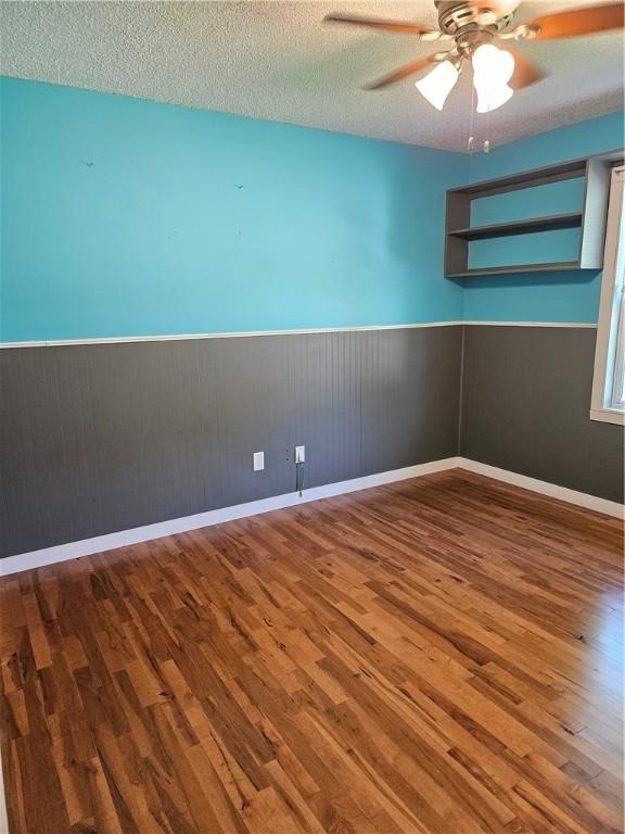 241 S Main St, Argenta, IL 62501 - unfurnished room featuring wainscoting, wood finished floors, ceiling fan, and a textured ceiling