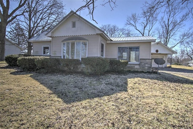 view of front facade featuring stone siding, metal roof, and a garage