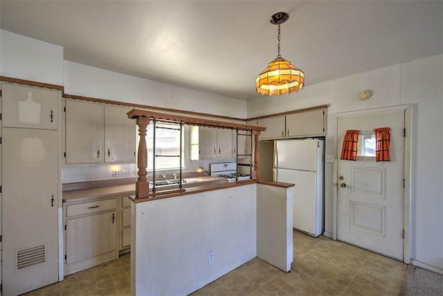 kitchen featuring hanging light fixtures, light floors, visible vents, and freestanding refrigerator