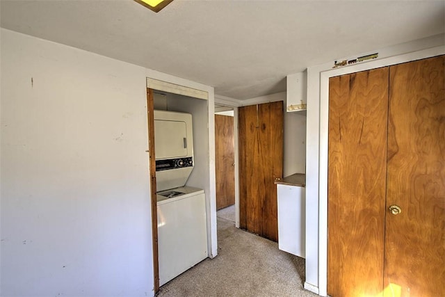 laundry area with laundry area, stacked washer / dryer, and light carpet