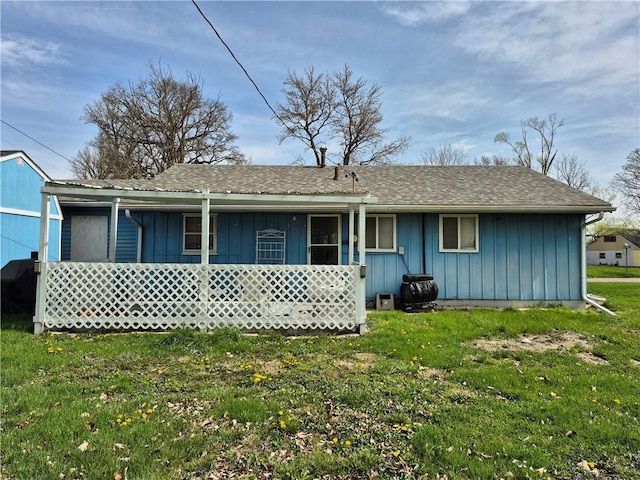 rear view of property featuring a lawn, board and batten siding, and covered porch