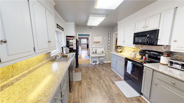 215 E Winter Ave, Danville, IL 61832 - kitchen with black appliances, light wood-style floors, decorative backsplash, and white cabinets