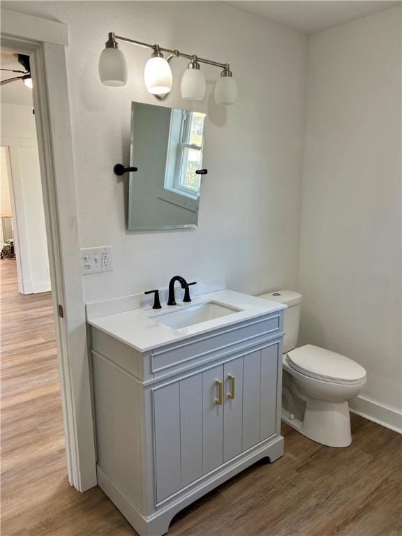 bathroom featuring ceiling fan, wood-type flooring, toilet, and vanity