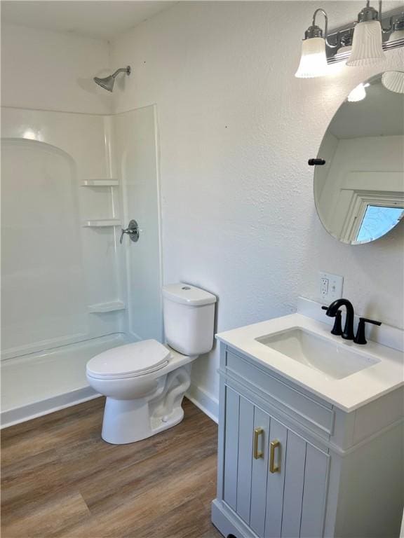 bathroom featuring vanity, wood-type flooring, toilet, and walk in shower