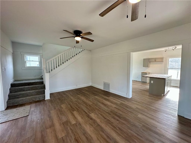 unfurnished living room with dark wood-type flooring, ceiling fan, and a healthy amount of sunlight