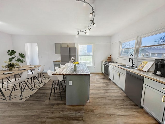 kitchen featuring sink, a breakfast bar area, appliances with stainless steel finishes, gray cabinetry, and a center island