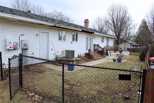 back of property featuring fence private yard, central AC, a lawn, and a chimney