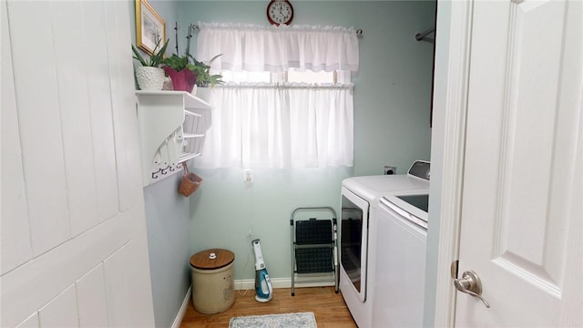 laundry area featuring laundry area, light wood finished floors, washing machine and clothes dryer, and a wealth of natural light