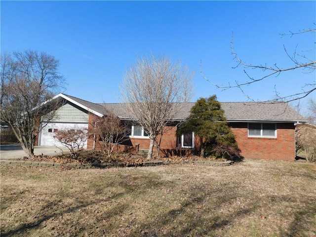 ranch-style home featuring an attached garage, roof with shingles, a front lawn, and brick siding