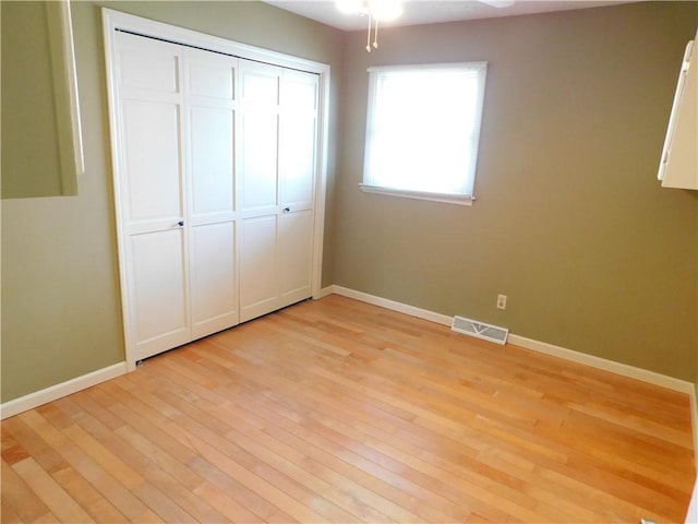 unfurnished bedroom featuring baseboards, visible vents, light wood-style flooring, and a closet