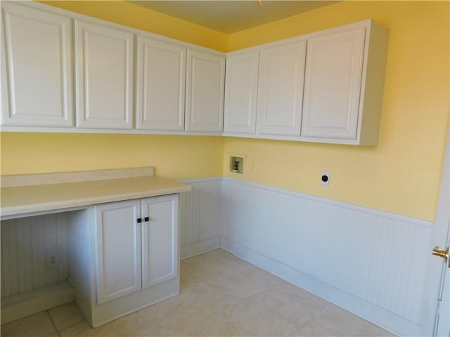 laundry room with washer hookup, a wainscoted wall, and cabinet space