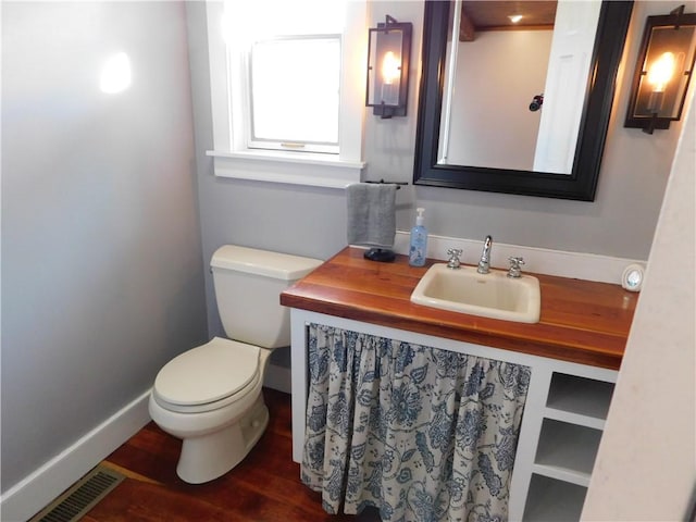 bathroom with baseboards, visible vents, toilet, wood finished floors, and vanity