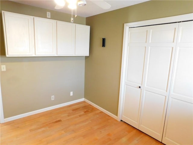 unfurnished bedroom featuring a ceiling fan, light wood-style flooring, baseboards, and a closet