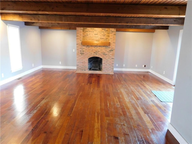 unfurnished living room with a fireplace, baseboards, hardwood / wood-style floors, and beamed ceiling